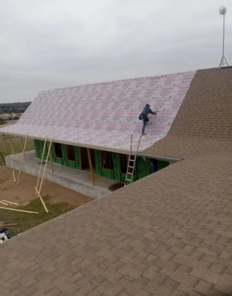 Worker preparing underlayment for a metal roof installation in Westford